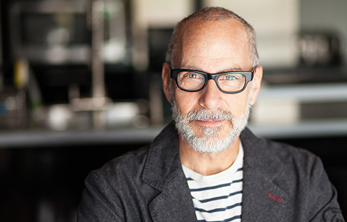 Mezczyzna w okularach z delikatnym usmiechem na twarzy 